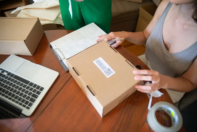 Online seller working on a laptop surrounded by packaging for a digital shop