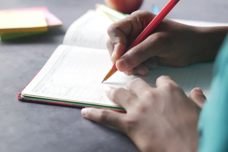 Close-up of a hand writing in a planner or notebook