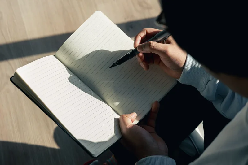 Creator evaluating product ideas in a notebook next to a laptop