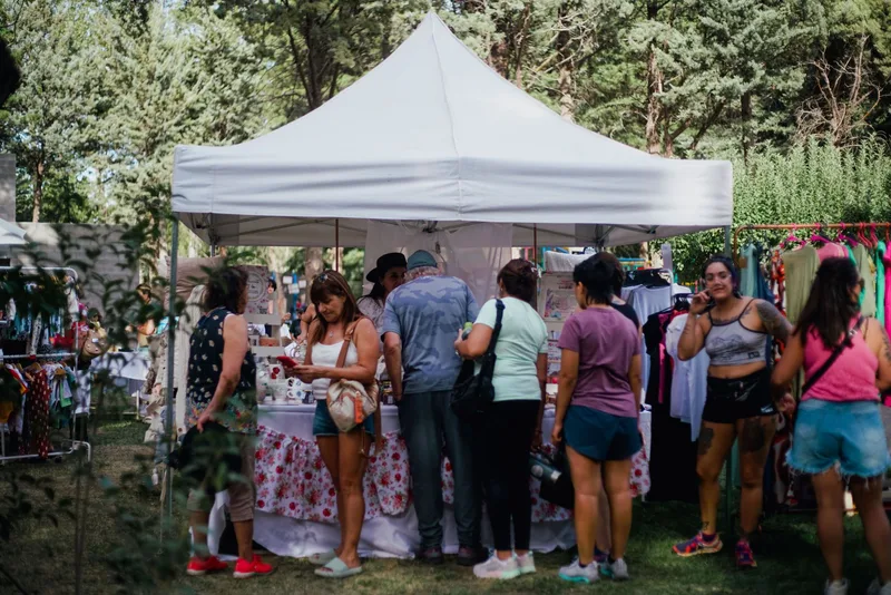 Outdoor market stall with visitors browsing handmade goods and prints