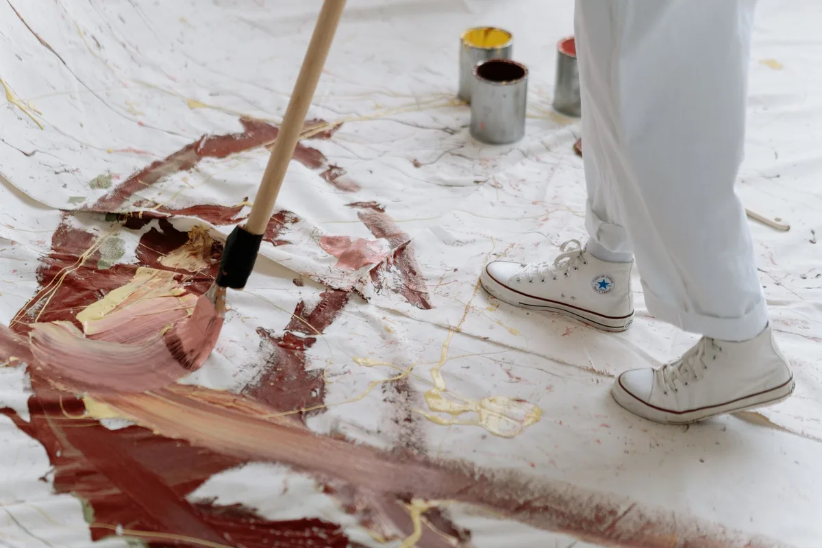 Artist mixing paint and working on an abstract canvas in a studio