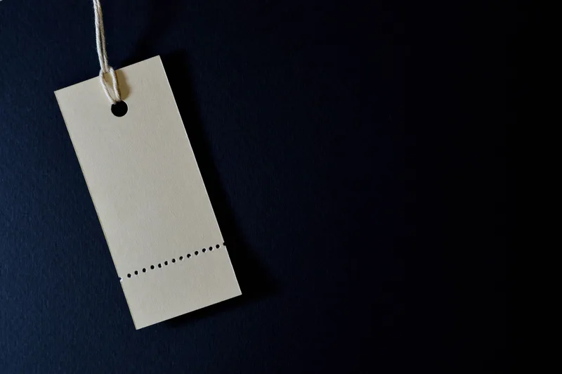 Blank price tag on a string against a dark background