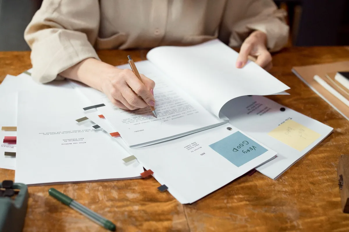 Close-up of hands writing and organizing manuscript pages on a desk