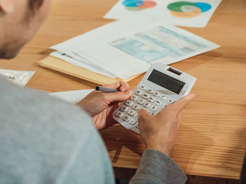 Person using a calculator at a desk with financial documents