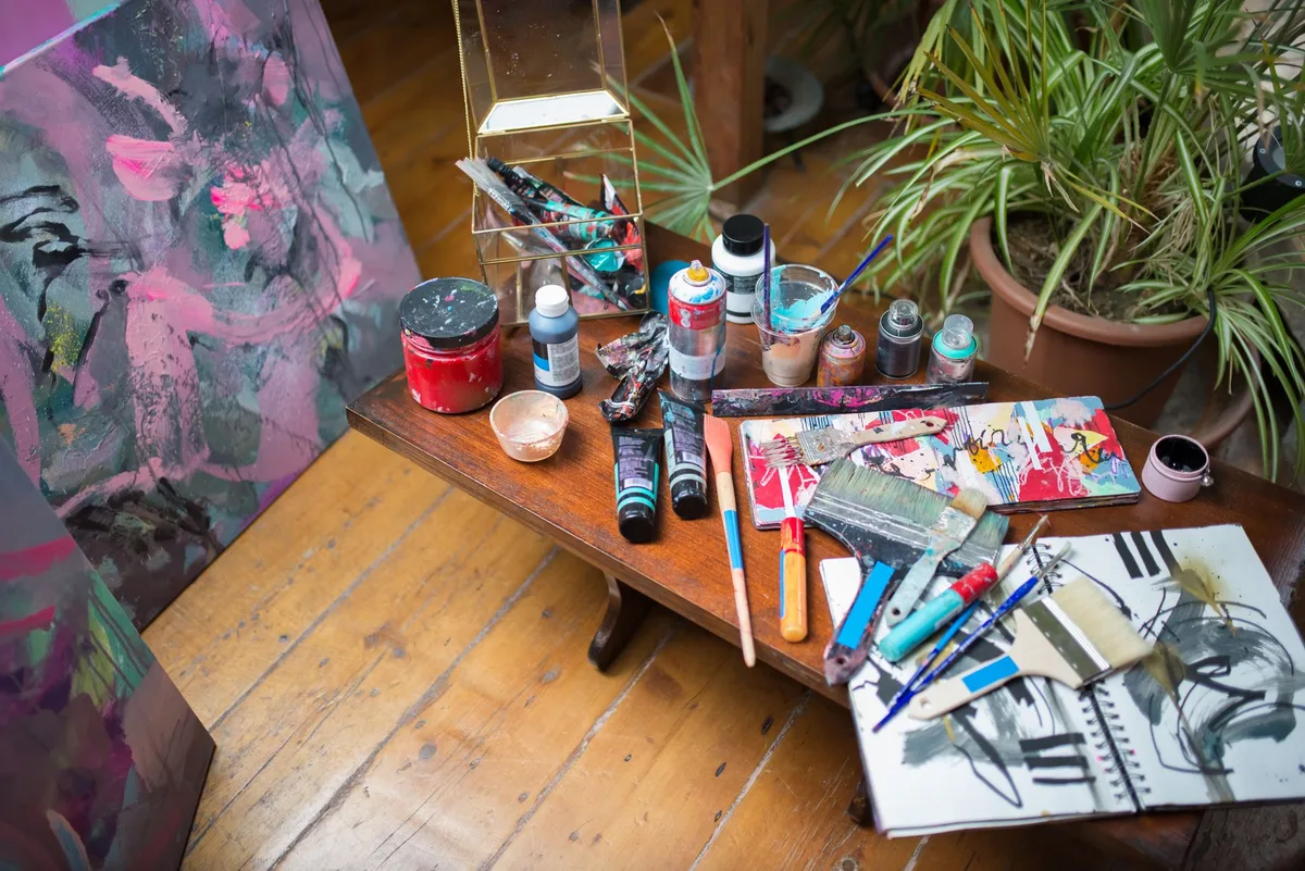 Art supplies and abstract paintings in a colorful artist studio workspace