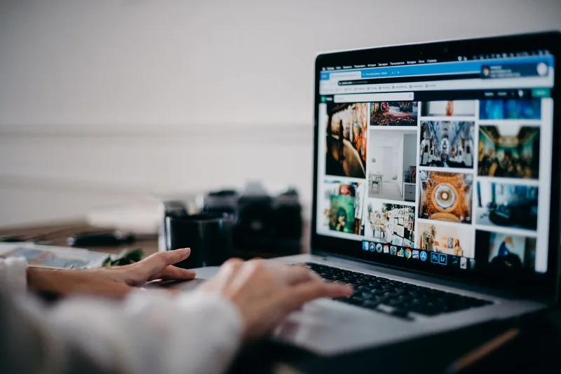 Person browsing stock photos on a laptop while managing a digital products store