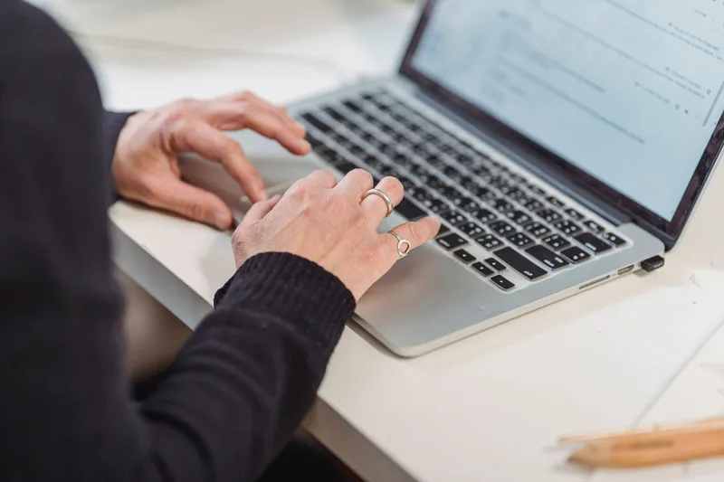 Close-up of hands typing on a laptop keyboard, representing the focused work of populating a template with sample data and documentation