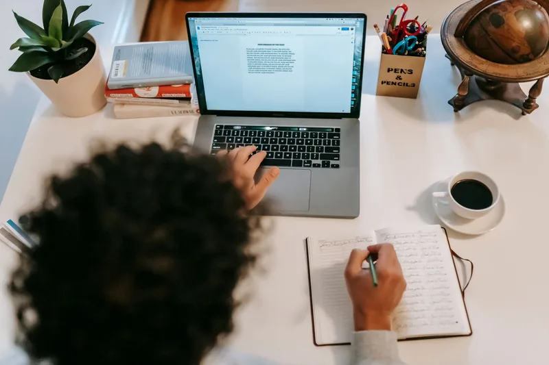 Freelance writer typing on a laptop next to a cup of coffee