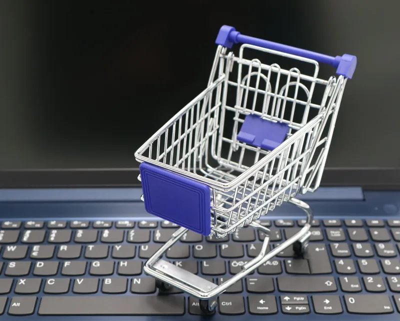 Mini shopping cart on a laptop representing digital e-commerce setup