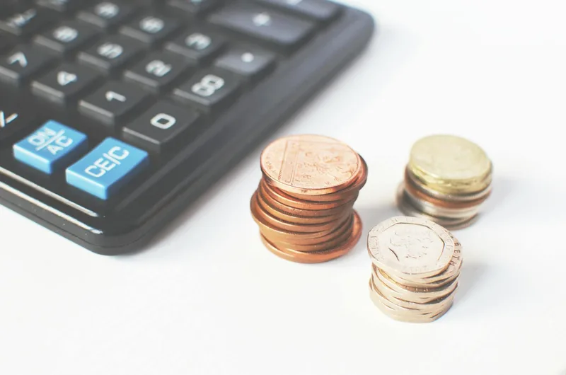 Coins and calculator representing fee comparison between platforms