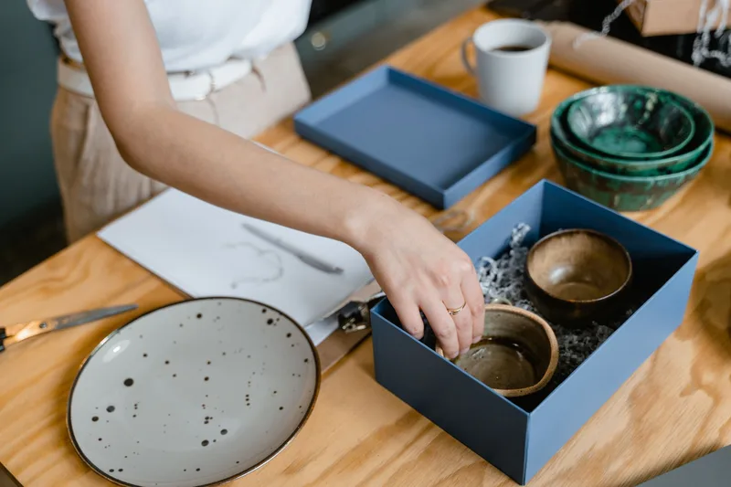 Artisan packing handmade ceramic products for marketplace fulfillment
